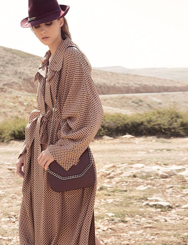 فستان على شكل المعطف من الحرير المطبع، وحقيبة باللون البرغندي وقبعة من Stella McCartney.