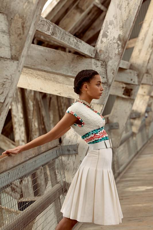 توب من التويد العاجي مطرز بالبرق اللماع حزام عاجي من الجلد والمعدن تنورة بيضاء مثناة من الكريب عقد من المعدن الذهبي والراتنج والجلد والخرز الزجاجي والستراس