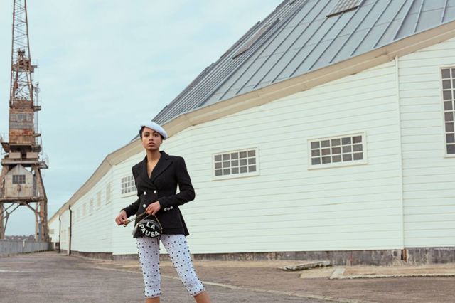 قبعة من التويد العاجي سترة سوداء من الكريب الصوفي اللماع سروال أبيض من القطن المطرز حقيبة من الجلد والمعدن باللونين الأسود والأبيض.