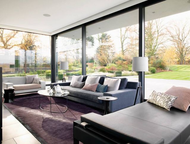 صالة أخرى للجلوس تتصدرها كنبات وثيرة من اللون البيج والرمادي الداكن، وتزّينها عناصر فاخرة للإضاءة