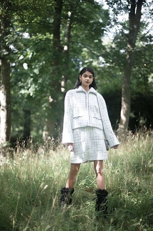 سترة من التويد الأبيض والرمادي والأسود مزينة بالضفائر والأزرار المجوهرة تنورة من التويد الأبيض والرمادي والأسود مزينة بالضفائر والأزرار المجوهرة أقراط من المعدن والراتنج والستراس جزمة سوداء من الصوف والجلد