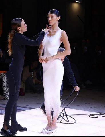 بالفيديو - بيلا حديد تثير الجدل بظهورها عارية وبرشّ فستان أبيض على جسدها