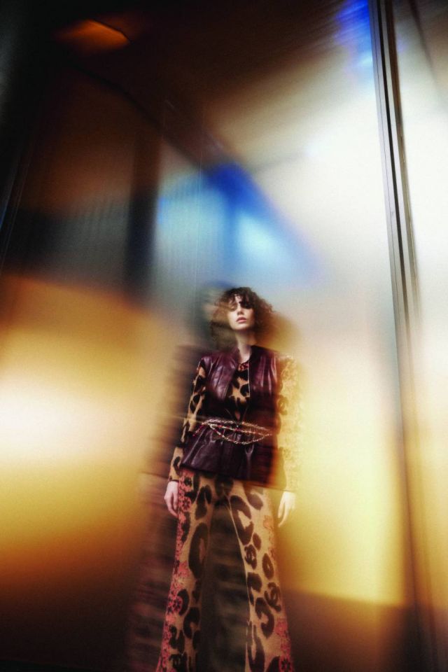 سترة من دون كمين من الجلد البرغندي  كنزة من الكشمير والموهير البيج والأسود والبرتقالي  سروال من الكشمير والموهير البيج والأسود والبرتقالي  حزام من المعدن والخرز الزجاجي. الكل من شانيل CHANEL