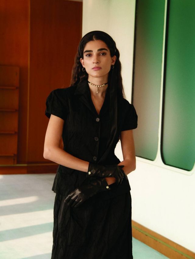 عصبة سوداء للرأس، أقراط للأذنين، عقد، سترة سوداء بكمين قصيرين، تنورة سوداء، قفازات سوداء، من Dior