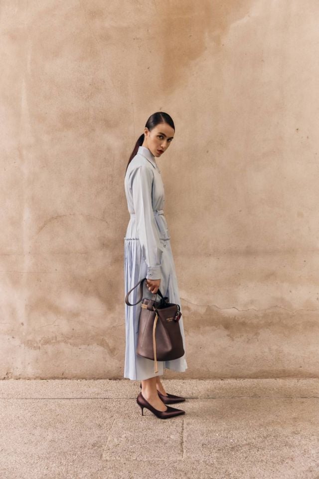 فستان بثنيات من البوبلين وحذاء من الساتان وحقيبة Bucket من الجلد من Prada 
