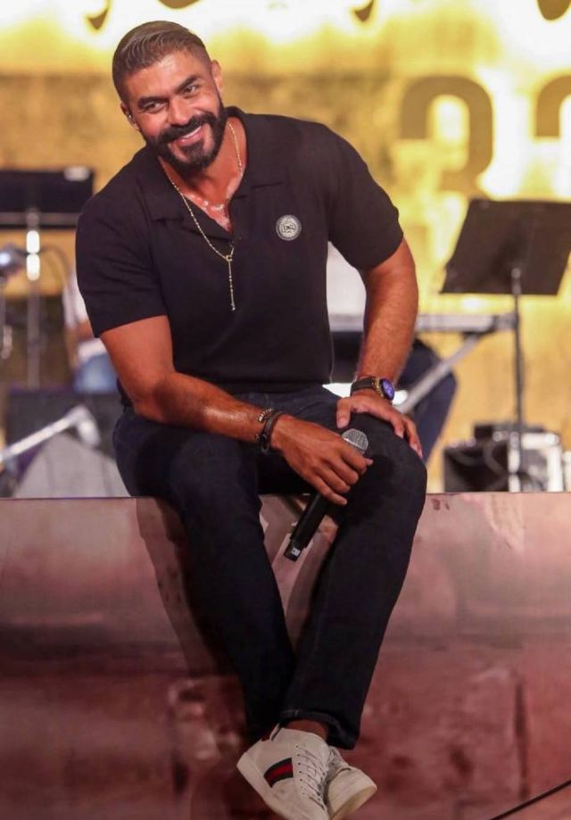 خالد سليم جالساُ على حافة المسرح ويمازح الجمهور