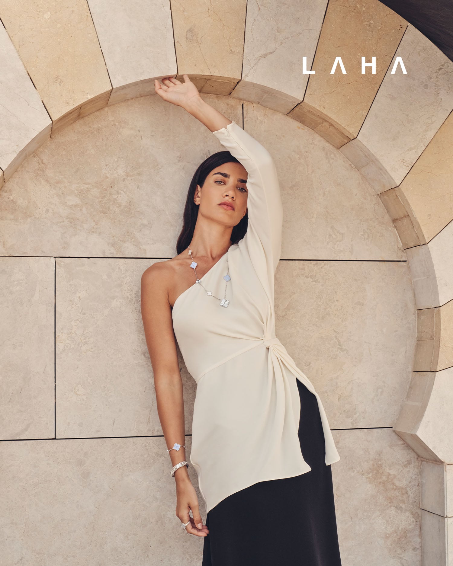 عقد ماجيك ألامبرا الطويل قابل للتحويل، مكوّن من 15 حلية زخرفية، مصنوع من الذهب الأبيض عيار 18 قيراطاً مطليّ بالروديوم بزخرفة غيوشيه، ومرصع بالخلقيدونية وعرق اللؤلؤ الأبيض، سوار بيرليه كلوفرز من الذهب الأبيض عيار 18 قيراطاً مطليّ بالروديوم، مرصّع بالماس الدائري، الموديل المتوسط، خاتم فينتاج ألامبرا قابل للارتداء على الوجهين، مصنوع من الذهب الأبيض عيار 18 قيراطاً مطليّ بالروديوم بزخرفة غيوشيه، ومرصع بالخلقدونية وقطع الماس من فان كليف أند آربلز  توب وتنورة من Valentino