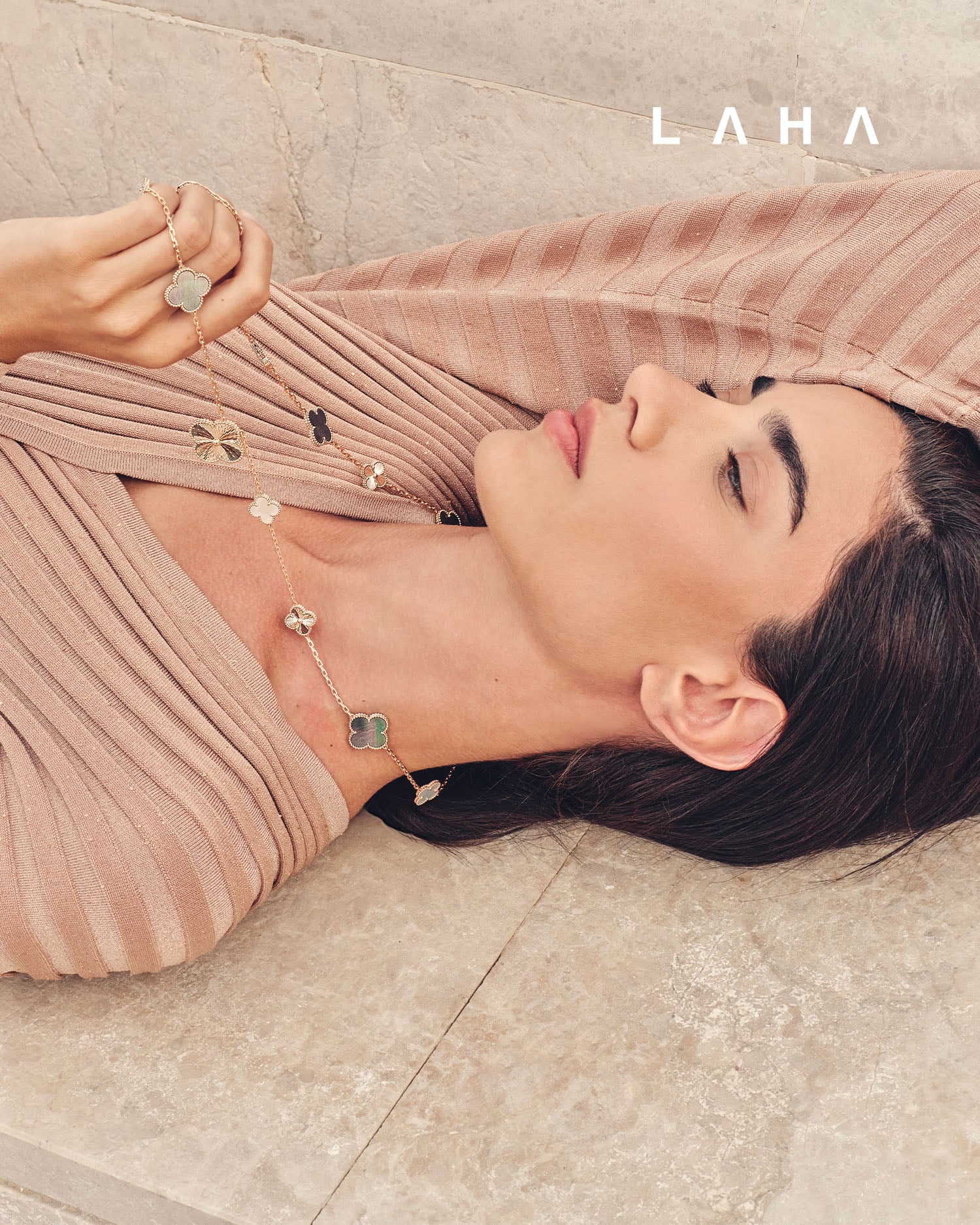 عقد ماجيك ألامبرا طويل قابل للتحويل، مكوّن من 15 حلية زخرفية، مصنوع من الذهب الوردي عيار 18 قيراطاً بزخرفة غيوشيه، ومزيّن بعرق اللؤلؤ الأبيض والرمادي من فان كليف أند آربلز  فستان من NÓRA 