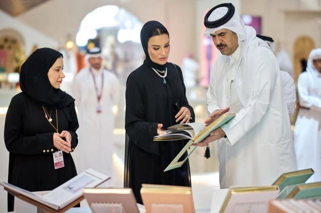 الشيخة موزا بنت ناصر تتصفح كتاباً في معرض الدوحة الدولي للكتاب، متألقة بعباية سوداء انسيابية وعقد لؤلؤ فاخر مرصع بحجر كريم أزرق.