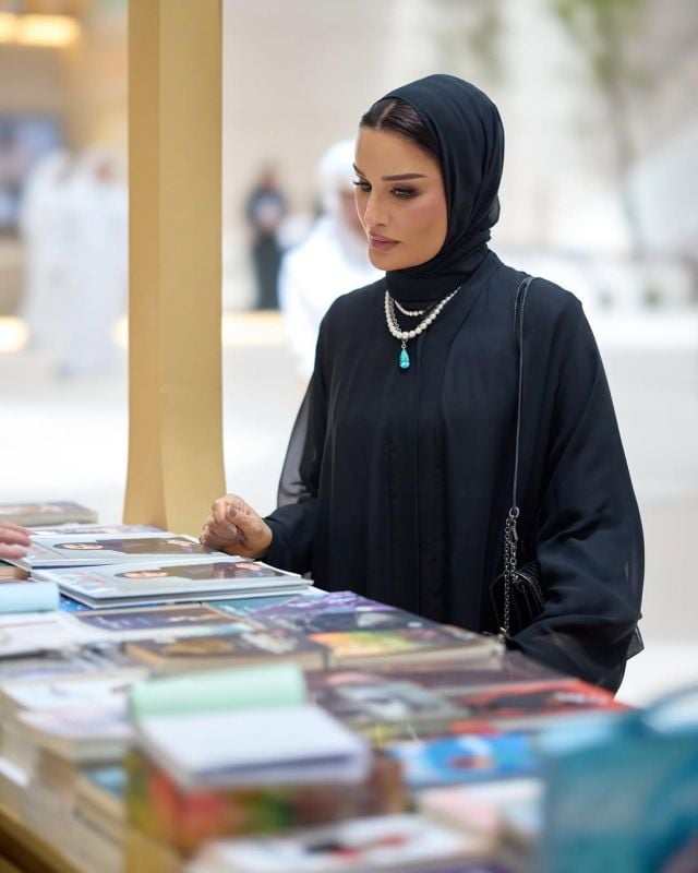تفاصيل مكياج الشيخة موزا بنت ناصر الأنيق والعمامة السوداء، مع تركيز على مجوهرات اللؤلؤ وتصميم الأكمام الشفافة خلال زيارتها لمعرض الكتاب.