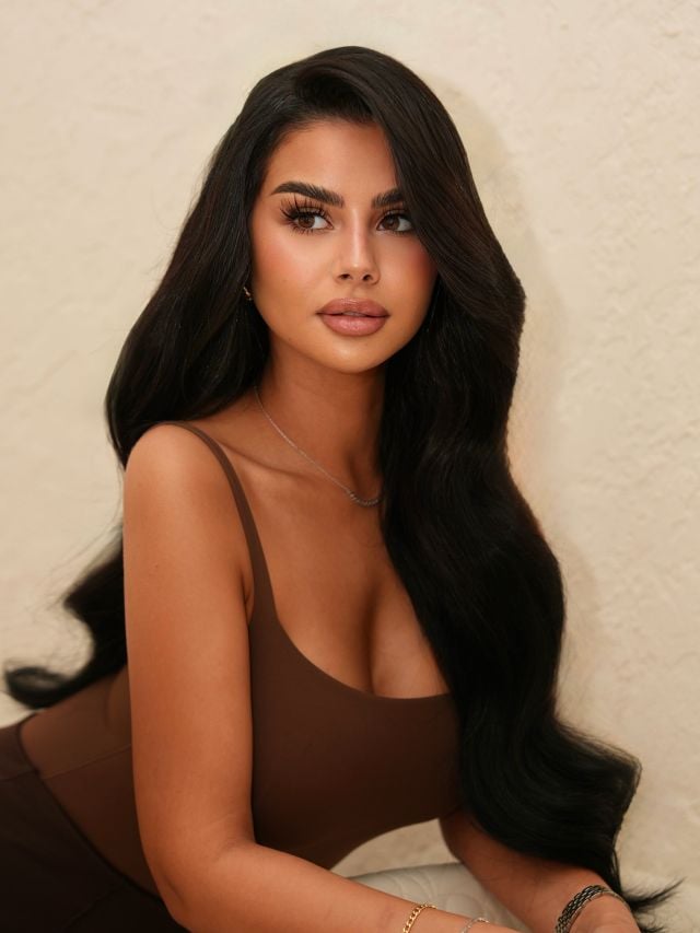 منة عرفة بمكياج ترابي وشعر أسود مموج وتوب بني.