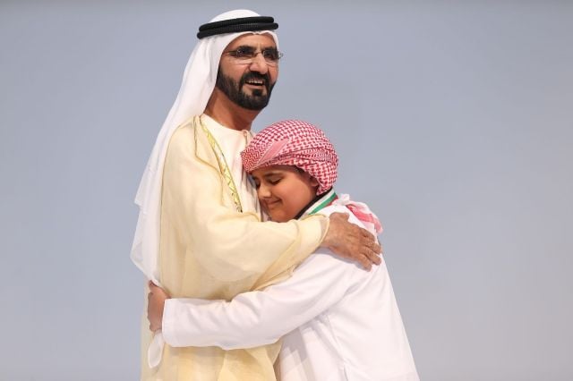 الشيخ محمد بن راشد محتضنا الطفل أديب البلوشي