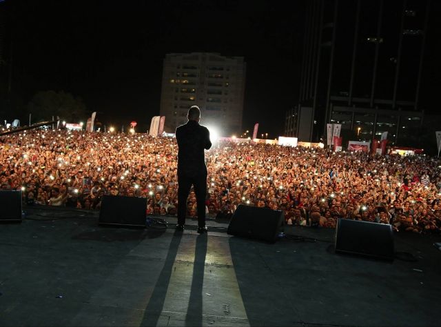 في حفلته بدبي: عمرو دياب يداعب فرقته ومعجبة تحمل رسماً لوجوه أبنائه الأربعة