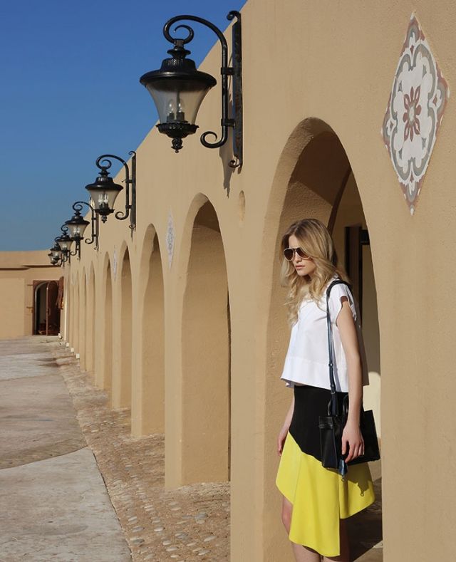 تنورة باللونين الأسود والأصفر، وبلوزة بيضاء، وحقيبة، ونظارات شمسية من Balenciaga.