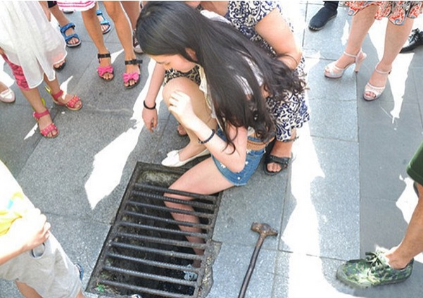 بالصور- علقت قدمها بقناة الصرف بسبب الهاتف