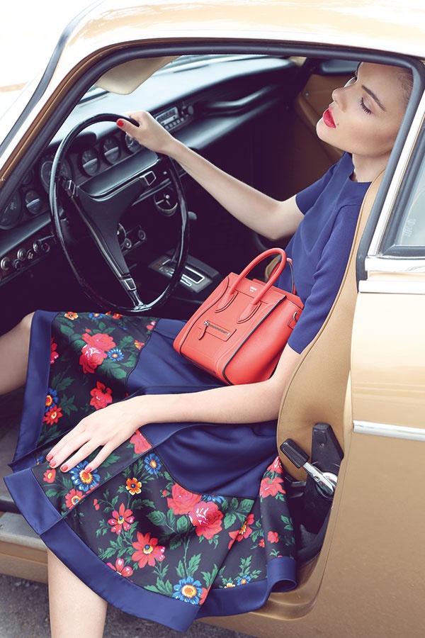 تنورة من الحرير الكحلي اللون المطبع بالأزهار، وتوب من النسيج المحبوك وحقيبة من الجلد. الكل من Celine.
