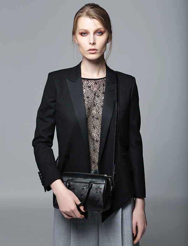 بلوزة من الشبك الشفاف وسترة سوداء وحقيبة من الجلد من 
Saint Laurent.
