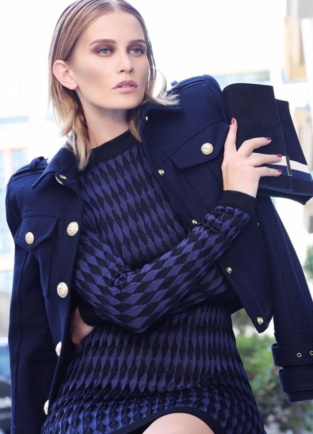 فستان من النسيج المحبوك وسترة عسكرية من BALMAIN. حقيبة صغيرة من TOMASINI.
