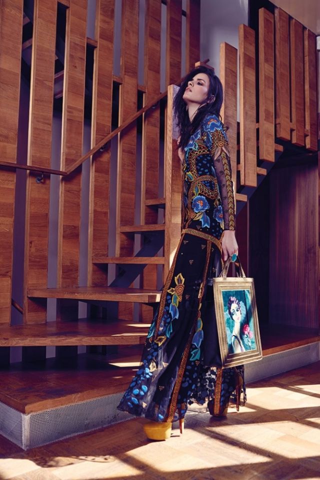 فستان طويل مطرز من Temperley London. حقيبة على شكل لوحة فنية مؤطرة من Charlotte Olympia. حذاء من الجلد السويدي الخردلي اللون من Christian Louboutin. خاتم من Pebble London.
