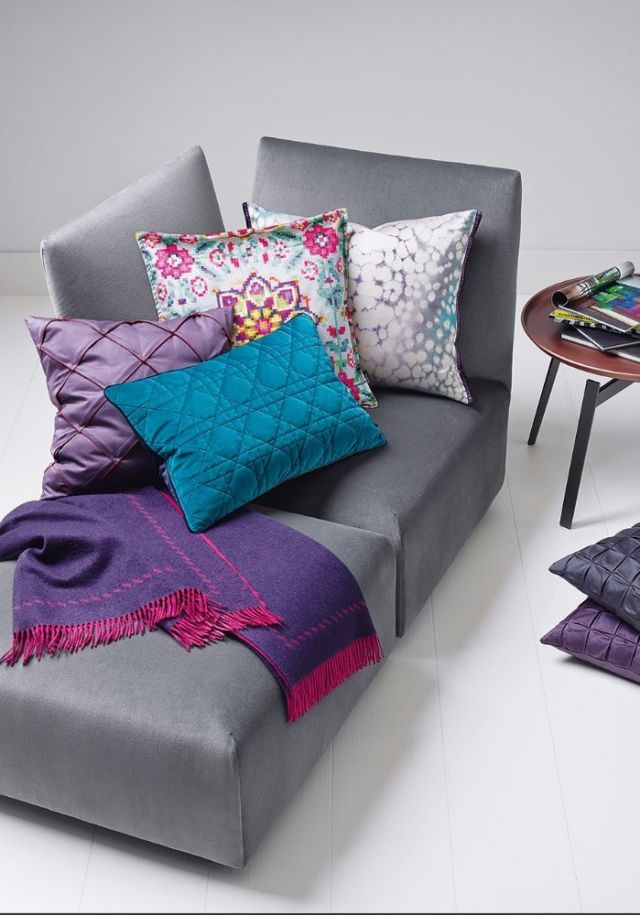 مقعد من القماش الرمادي تزيّنه وسائد ملوّنة