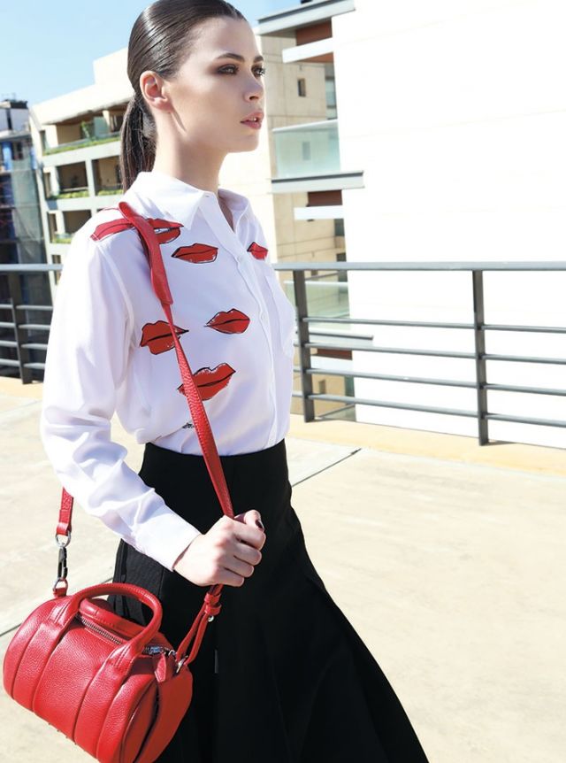 تنورة سوداء وحقيبة من الجلد الأحمر من Alexander Wang. قميص من الحرير من Equipment.
