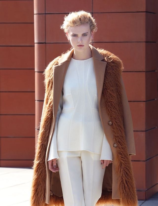 سروال وتوب من الكريب الصوفي الأبيض ومعطف من الصوف والفرو الزائف، الكل من Stella McCartney.
