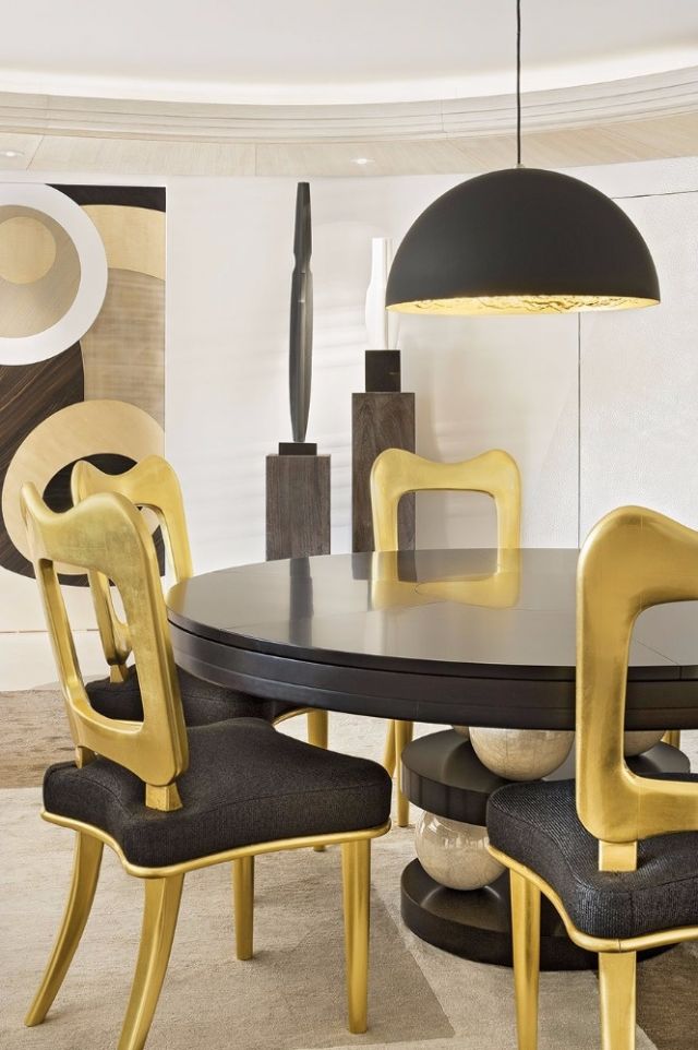 صالة الطعام منسّقة بقطع مبتكرة من الأثاث باللونين الأسود  والذهبي