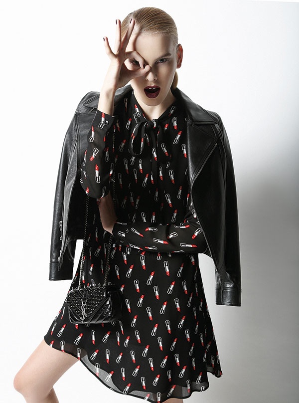 فستان من كريب الحرير المطبع بأحمر الشفاه، وسترة جلدية قصيرة وحقيبة صغيرة مزينة بالمسامير. 
الكل من Saint Laurent.
