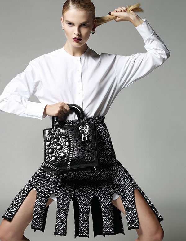 قميص أبيض وتنورة من النسيج المحبوك وحقيبة من الجلد وأقراط للأذنين.
 الكل من Dior.
