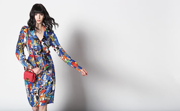 فستان من الحرير المطبع بشخصيات كرتونية، مع حزام وحقيبة صغيرة من الجلد. الكل من Moschino.
