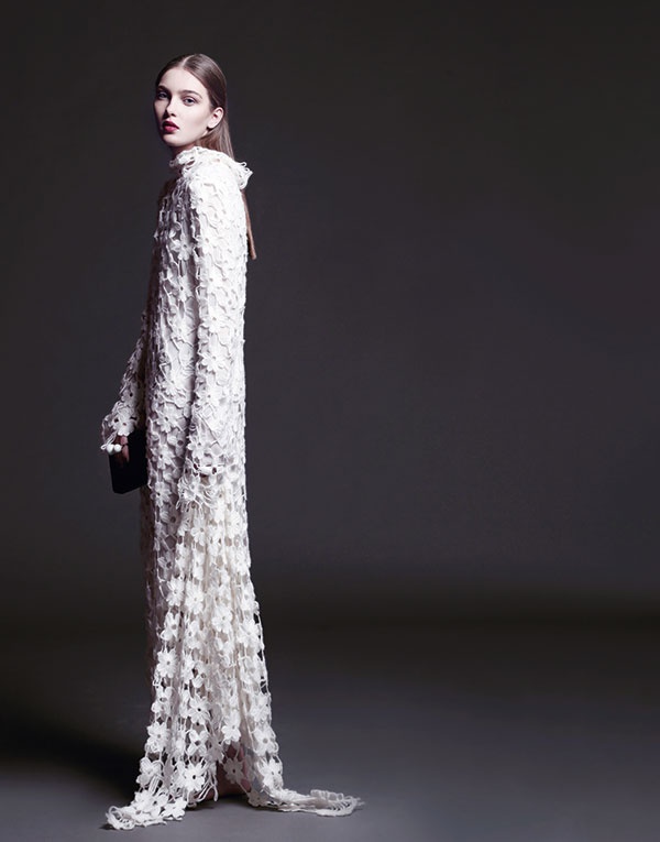 فستان طويل من كروشيه الصوف الأبيض وحقيبة يد من Stella McCartney.
