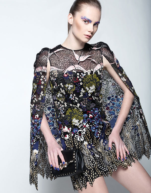 فستان على شكل رداء من الدانتيل المطرز وحقيبة من الجلد المزين بالمسامير من Valentino.
