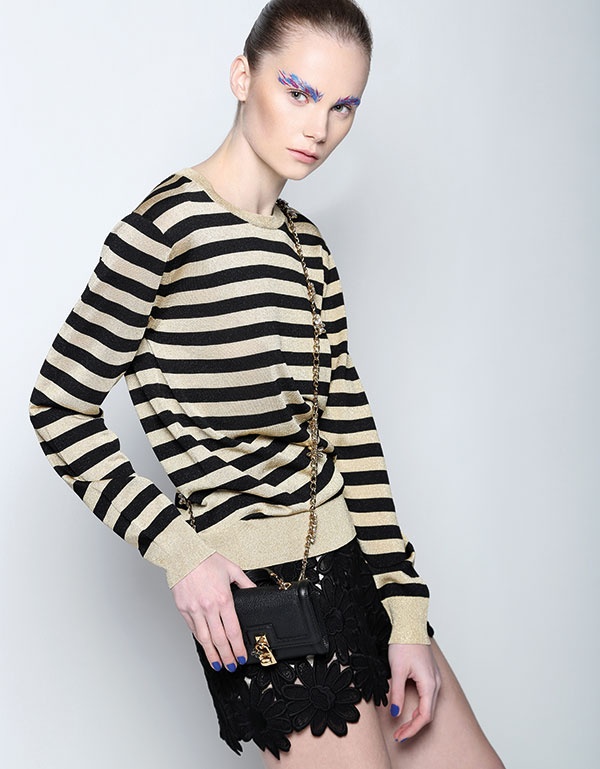 شورت من الدانتيل وكنزة مقلمة وحقيبة من Dolce&Gabbana.
