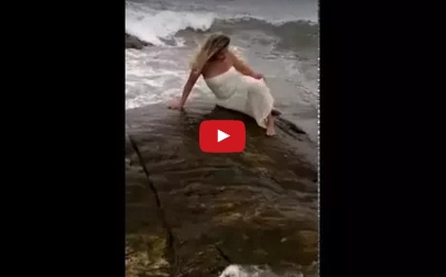 بالفيديو - موجة تبتلع حسناء تستعرض على الشاطىء