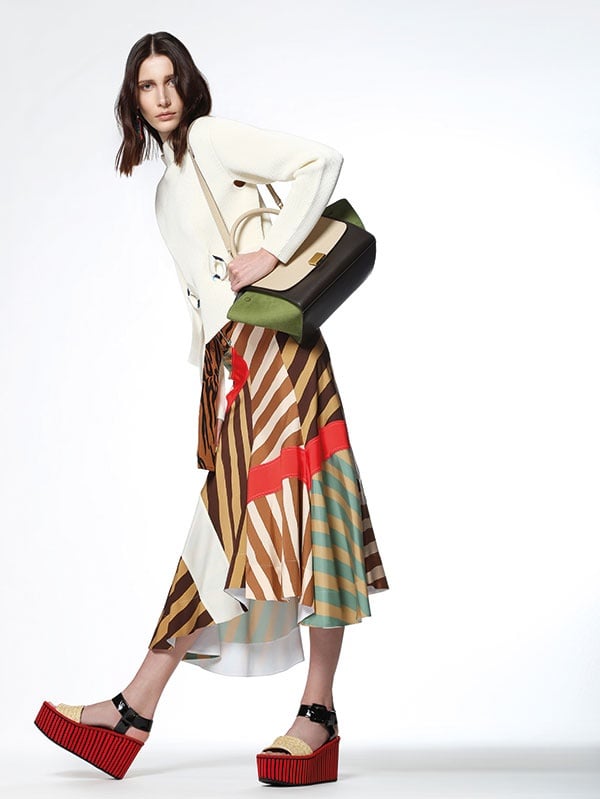 توب من النسيج العاجي المحبوك مع تنورة مخططة بألوان متعددة. حقيبة من الجلد وحذاء. الكل من Celine.
