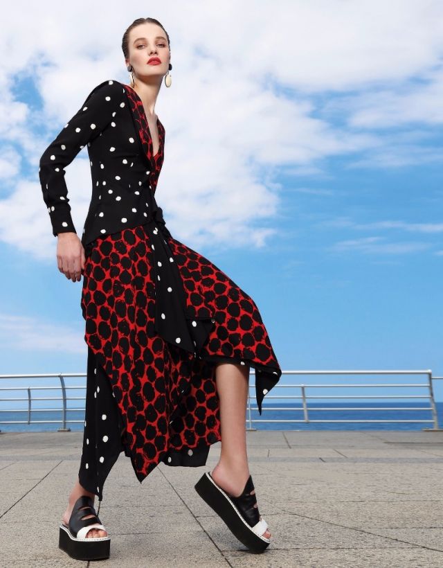 فستان مطبع بالنقاط من الكريب الأسود والأبيض، والأحمر والأسود من Proenza Schouler. أقراط للأذنين من Marni. حذاء من Fendi.
