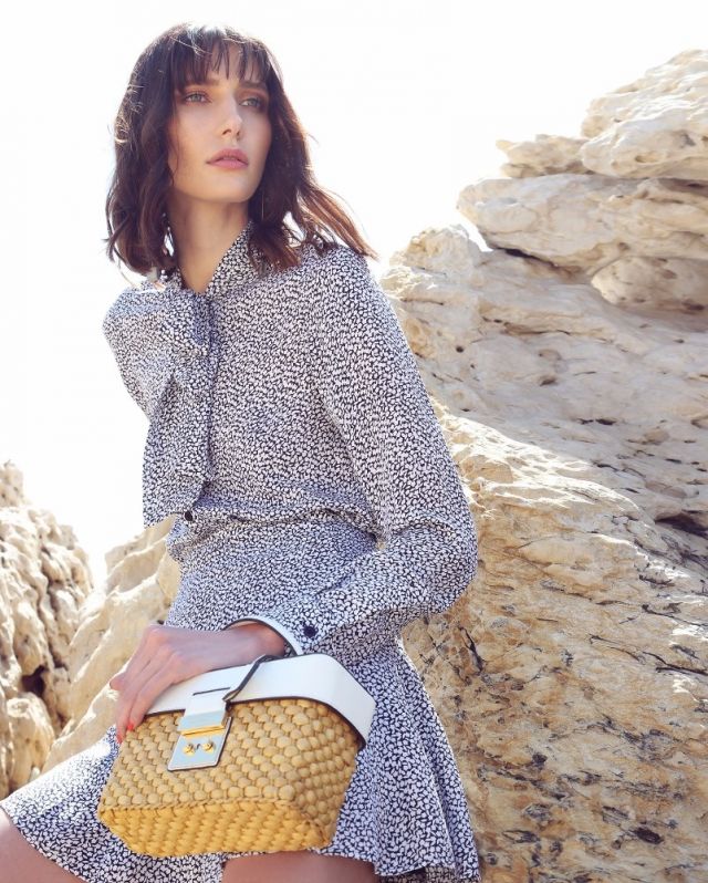 تنورة وبلوزة من الحرير المطبع، وحقيبة على شكل سلة. الكل من Michael by Michael Kors. 
