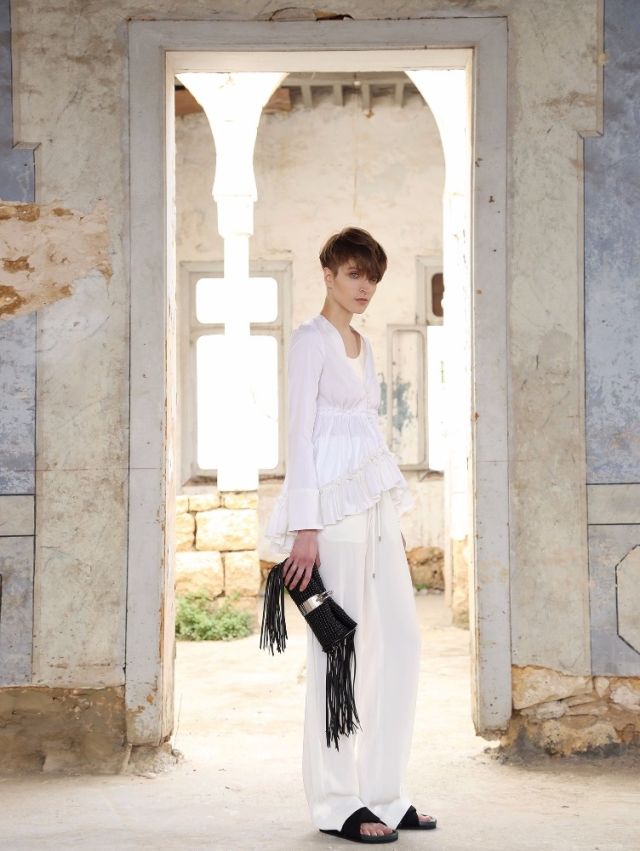 بلوزة من القطن الأبيض مع سروال من الكريب الأبيض. حقيبة من الجلد المزين بالشراريب. الكل من Balenciaga. حذاء من Celine.