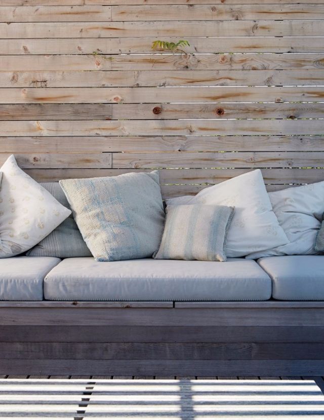 مقعد مريح في التراس تزيّنه وسائد مغطاة بأقمشة من الكتان