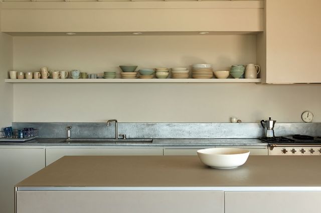 المطبخ تصميمه بسيط ومنسق بخزائن ورفوف من الخشب