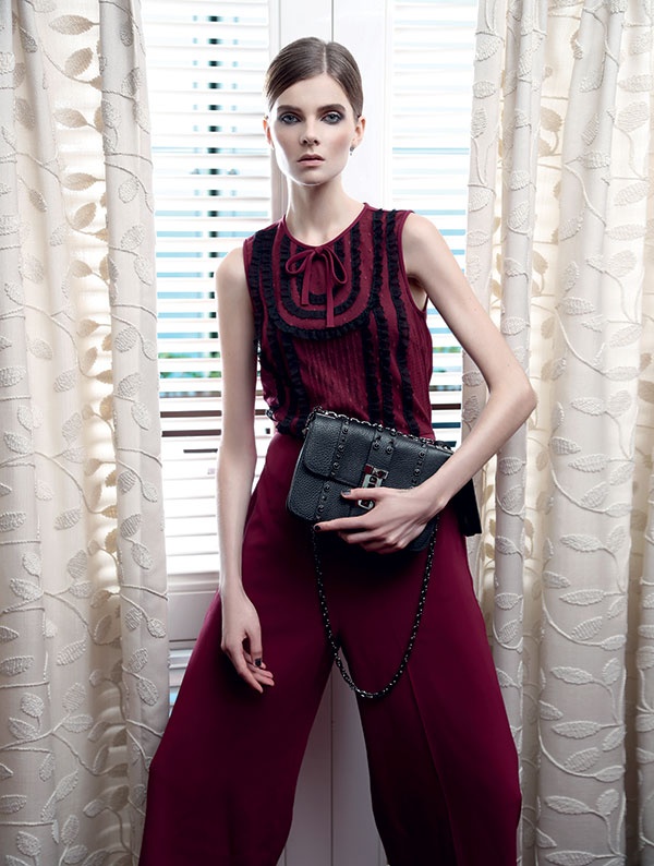 بذلة ذات قطعة واحدة من الجرسيه الأحمر الداكن والدانتيل الأسود من Red Valentino. حقيبة من الجلد المزين بالمسامير من Valentino.
