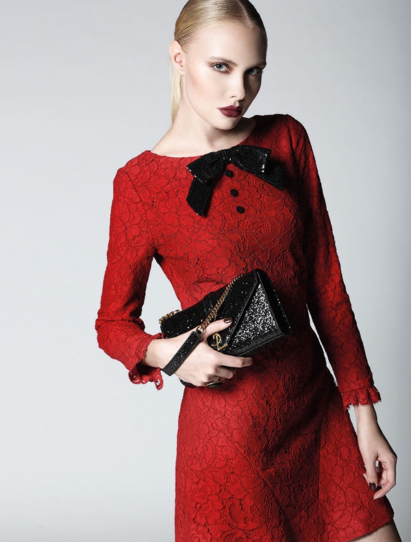 فستان من الدانتيل الأحمر مزين بعقدة من البرق اللماع الأسود وحقيبة. الكل من Saint Laurent.
