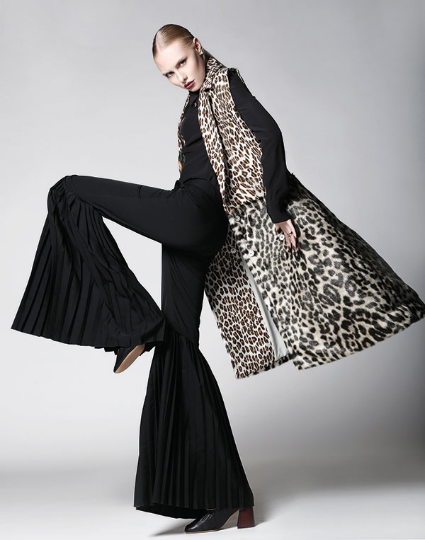 سروال واسع، وقميص من الحرير الأسود، وجيليه طويل مطبع بنقوش حيوانية. الكل من Stella McCartney. أقراط للأذنين من Dior. حذاء من Celine.
