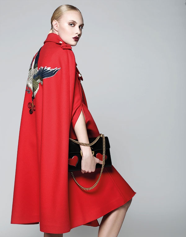 رداء أحمر مطرز على الظهر وحقيبة من الجلد من Gucci.
