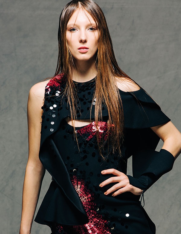 فستان سهرة أسود لافت للنظر. حواف لولبية ملتفة تؤطر الجسم بخطوط متعرجة. تطريزات يدوية دقيقة من البرق اللماع بألوان متدرجة من الوردي إلى الأحمر من ATELIER VERSACE.
