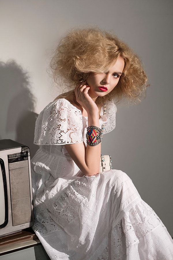 فستان من القطن والتخريم الانكليزي، وسوار عريض وحقيبة من الجلد المزين بالمسامير من Valentino.
