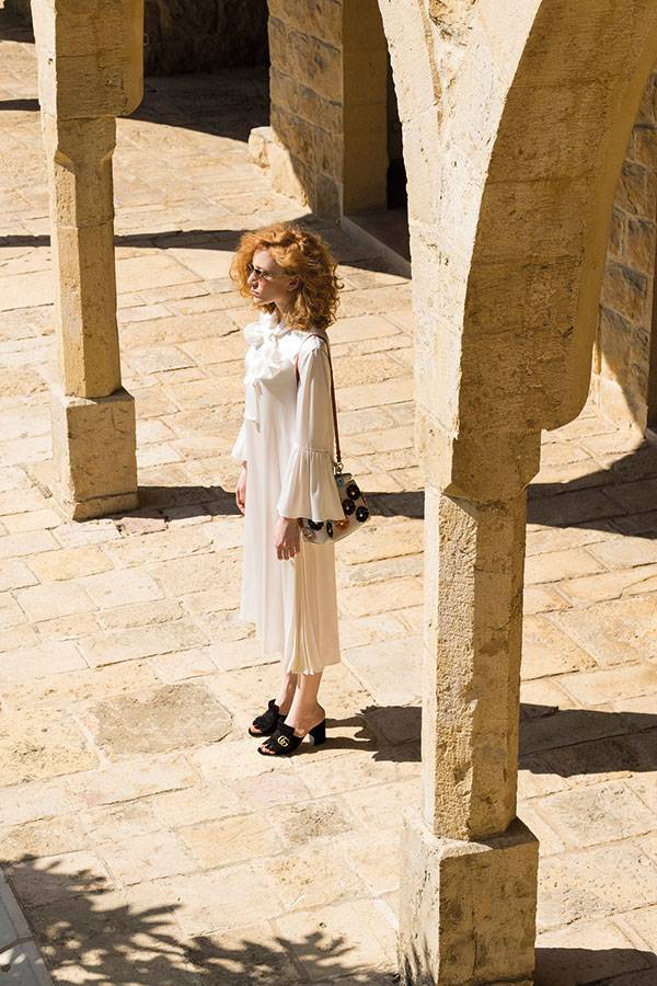 فستان من الحرير الأبيض، وحقيبة جلدية، ونظارات شمسية من Fendi. حذاء من Gucci.