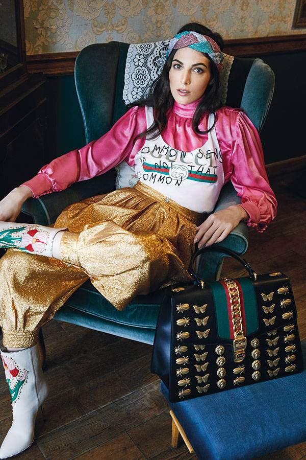 • بلوزة Coco Captain بيضاء اللون • قميص زهري من الحرير • سروال ذهبي • عصابة للرأس • جزمة بيضاء • حقيبة Sylvie الكل من Gucci